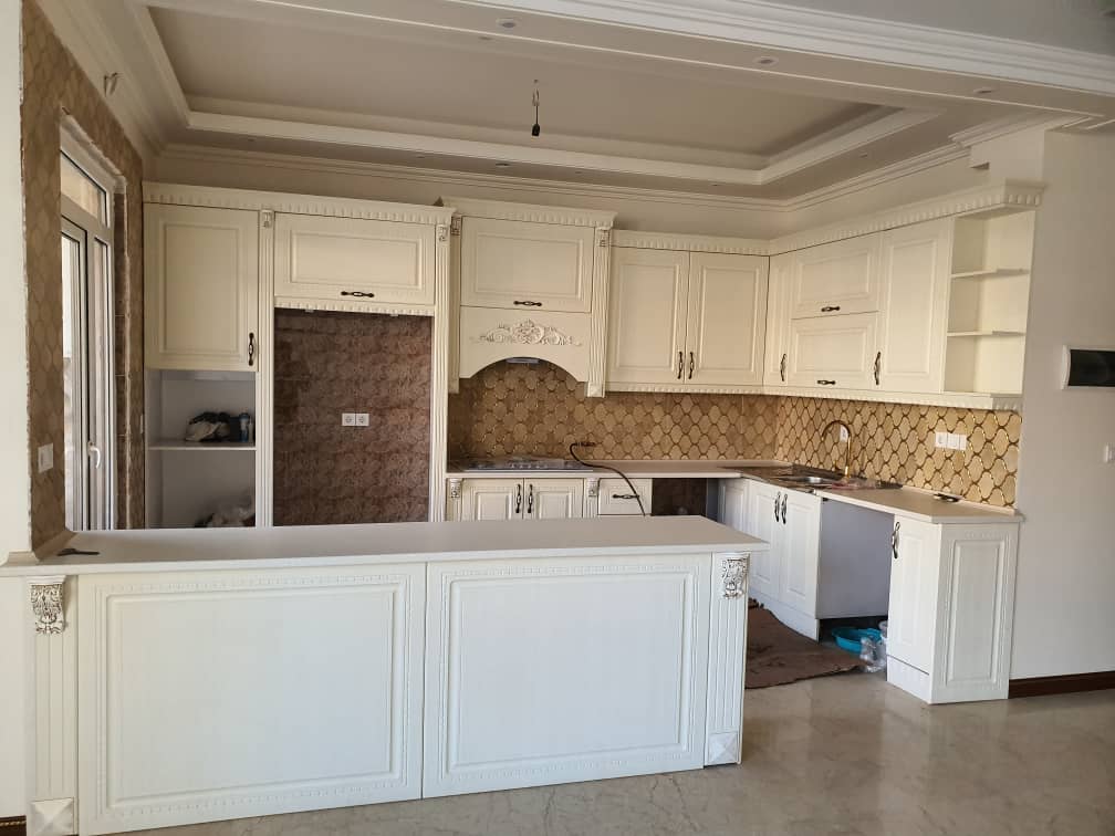 آشپزخانه در هر دو واحد با کابینت های مشابه سفید رنگ به سبک کلاسیک اجرا شده است